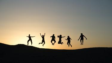 Sunset with family in silhouette leaping in the air