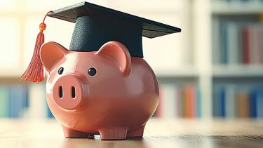 A pink piggy bank wearing a black graduation cap with a bookcase in the background